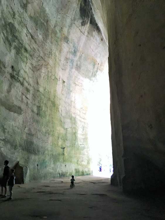 People exploring a cave at the Archaeological Park of Syracuse Sicily
